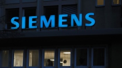 A logo sits illuminated above an office window at the Siemens AG gas turbine factory in Berlin, Germany, on Friday, Jan. 10, 2020. Siemens is considering the future of a controversial contract to supply signaling systems to a new Australian coal mine under pressure from environmental activists, who staged German-wide protests against the company on Friday. Photographer: Krisztian Bocsi/Bloomberg