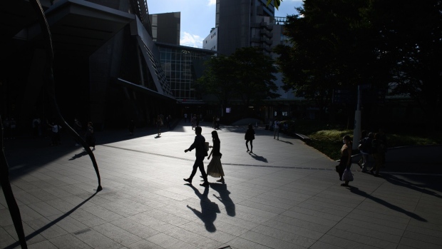 Silhouetted pedestrians near the Roppongi Hills complex in Tokyo, Japan, on Saturday, Oct. 1, 2022. Tankan business confidence and Tokyo CPI data at the start of the week will show the strength of price gains in September and the impact of inflation and global recession concerns on corporate activity. Photographer: Akio Kon/Bloomberg